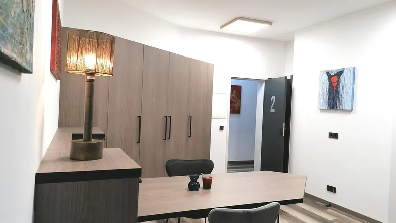 Moderner Büroraum mit großem Tisch, Stühlen und integrierten Schränken, gut beleuchtet.