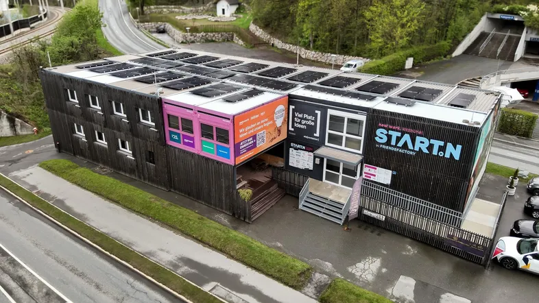 Moderne Gewerbeimmobilie mit Solarpaneelen auf dem Dach und umliegender Infrastruktur in grüner Umgebung.