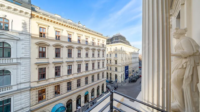 Blick von einem Balkon auf eine historische Stadtstraße mit klassischen Gebäudefassaden.