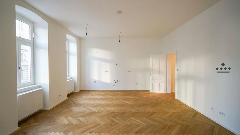 Heller, leerer Raum mit Fischgrätparkettboden und hohen Fenstern, ideal für Wohn- oder Schlafzimmer.