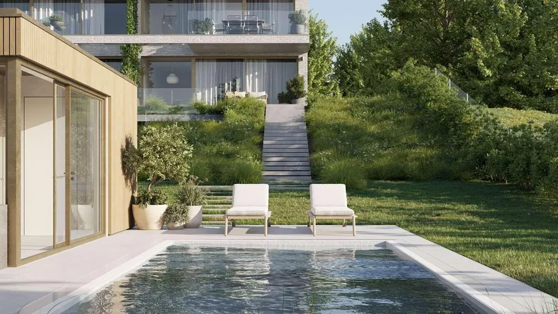 Moderner Außenbereich mit Swimmingpool, Liegestühlen und Blick auf das Hauptgebäude und die grüne Umgebung.