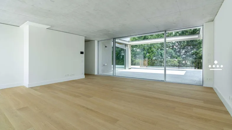 Heller, unmöblierter Wohnbereich mit Holzboden und großen Glasfronten zur Terrasse.