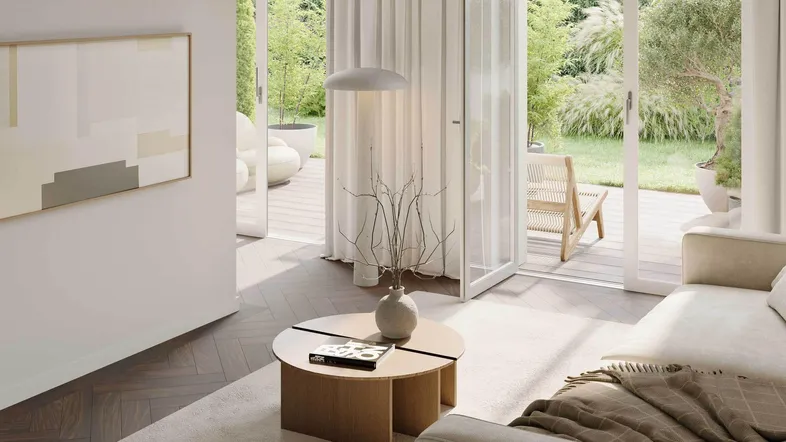 Lichtdurchflutetes Wohnzimmer mit beigem Sofa, Holztisch und großen Glastüren zum grünen Garten.