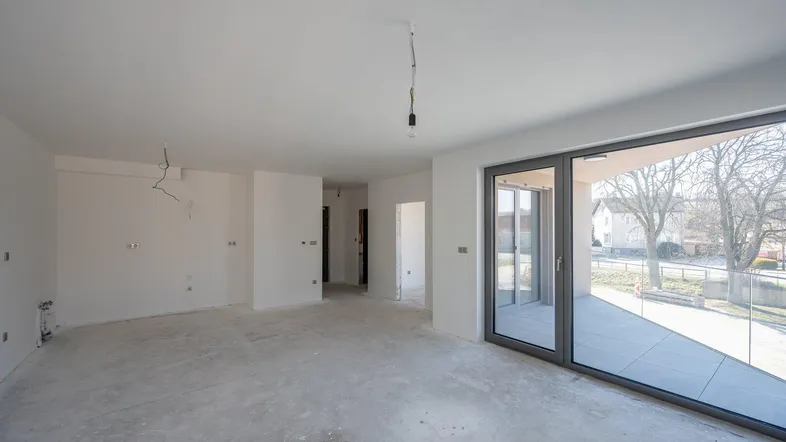 Unfertiger Wohnbereich mit großen Schiebetüren und Blick ins Freie, bereit für den Innenausbau.