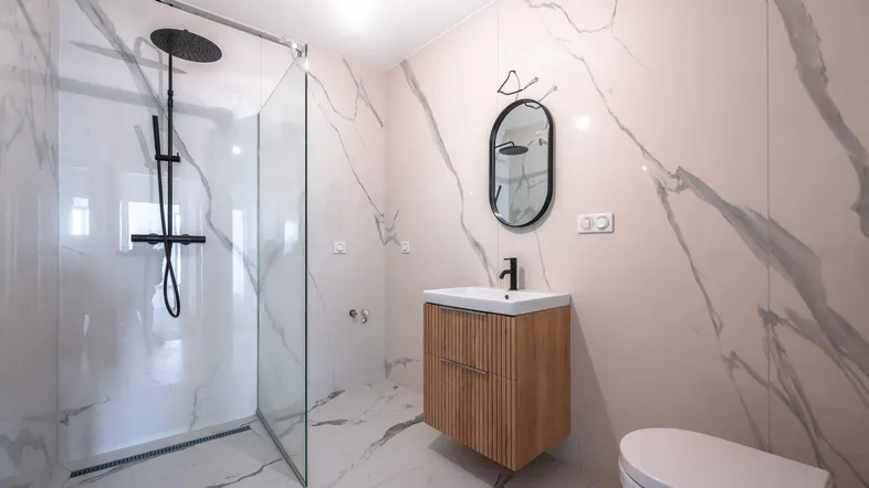 Modernes Badezimmer mit großformatigen Marmorfliesen, begehbarer Dusche und schwebendem Waschtisch.