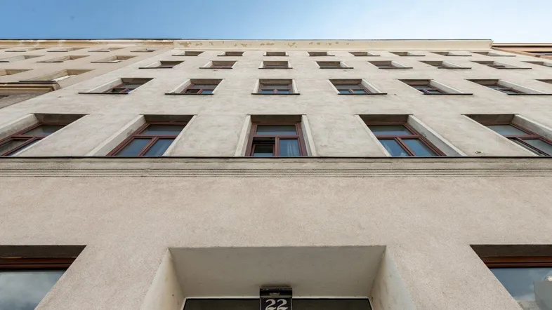 Ansicht der Gebäudefassade von unten mit vielen Fenstern und der Hausnummer 22.