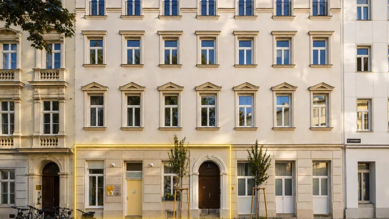 Historisches Gebäude mit klassischer Fassade und hervorgehobener Erdgeschosszone an der Straße.