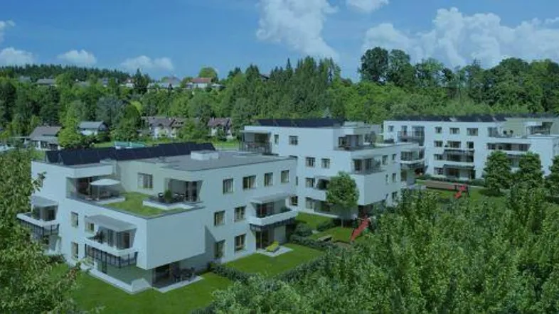 Moderne Wohngebäude mit Flachdächern, Balkonen und grüner Umgebung, umgeben von Bäumen und Natur.