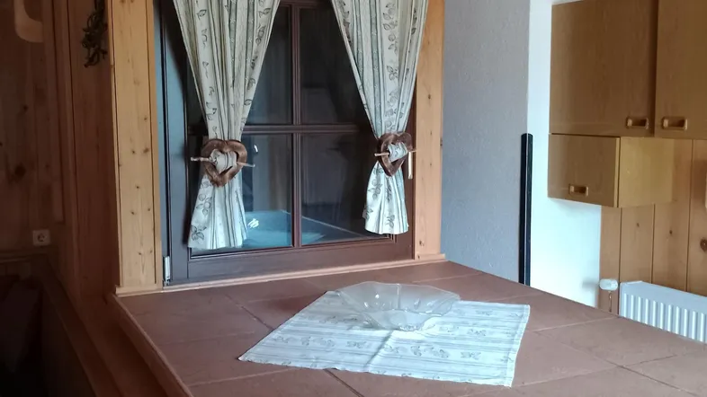 Gemütlicher Essbereich mit Holztäfelung, Fenster und traditionellen Vorhängen, ideal für Mahlzeiten.