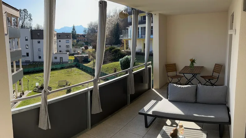 Heller Balkon mit Sitzgelegenheiten und Blick ins Grüne, ideal zum Entspannen im Freien.