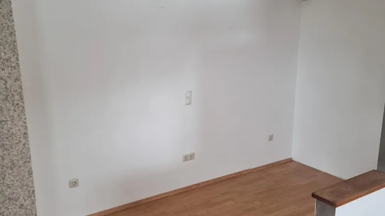 Heller Wohnraum mit Laminatboden und einer Akzentwand, bereit zur individuellen Gestaltung.