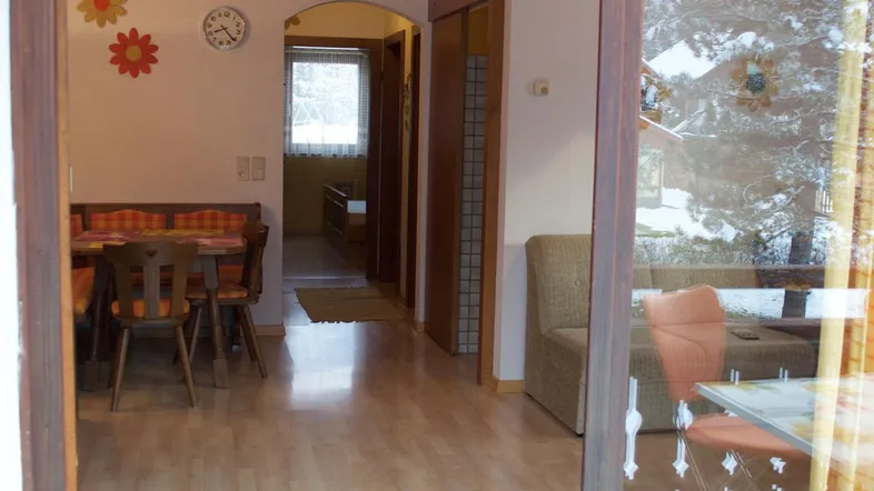 Blick durch die Glasschiebetür in einen gemütlichen Essbereich mit Holzbalkendecke und hellem Laminatboden.
