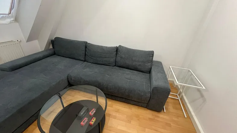 Gemütliches Wohnzimmer mit großem Ecksofa, Couchtisch und Dachschrägen.