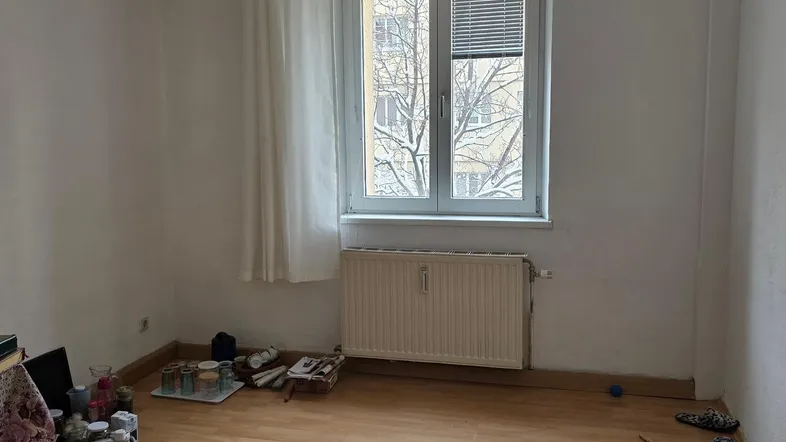 Heller Raum mit Laminatboden, Fenster und Heizkörper, bereit zur individuellen Gestaltung.