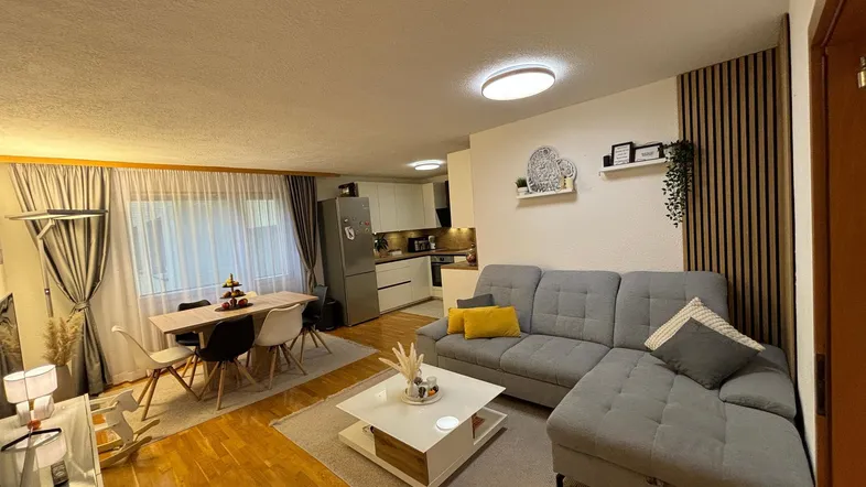 Offener Wohn- und Essbereich mit Sofa, Esstisch und integrierter Küche.