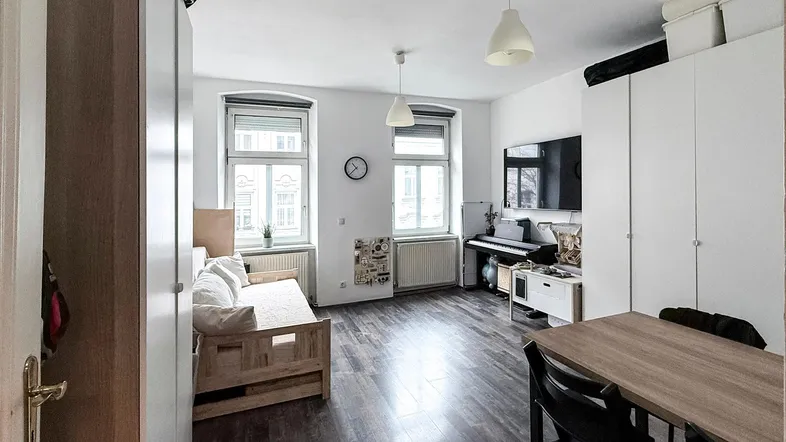 Geräumiger Wohn- und Essbereich mit dunklem Laminatboden, großen Fenstern und viel Stauraum durch weiße Schränke.