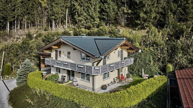 Traditionelles Haus in den Bergen mit Balkonen und umgeben von üppiger Natur und Wald.