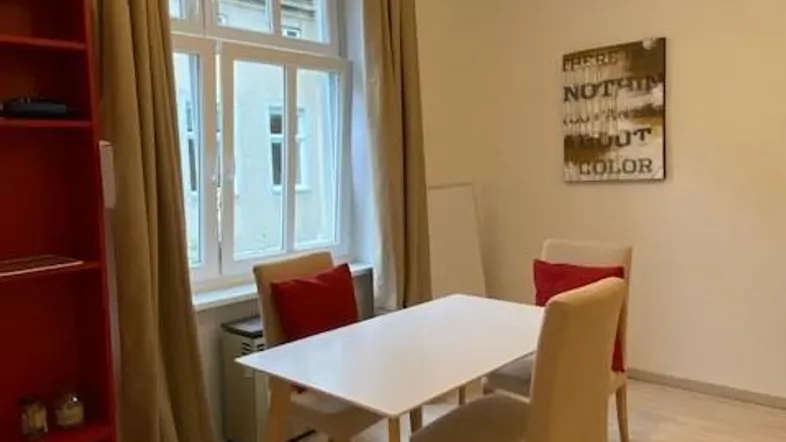 Heller Wohn- und Essbereich mit modernem Tisch, Stühlen und Blick auf die Straße durch das Fenster.