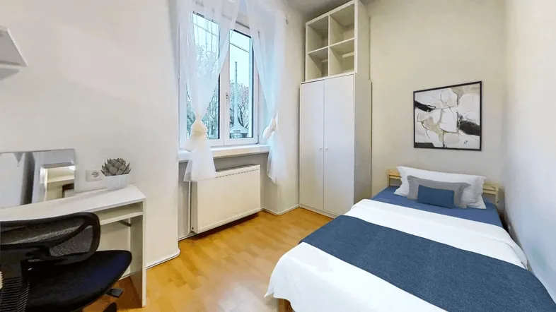 Helles Schlafzimmer mit Holzboden, Schreibtisch und Kleiderschrank, ideal für Studenten oder Einzelpersonen.