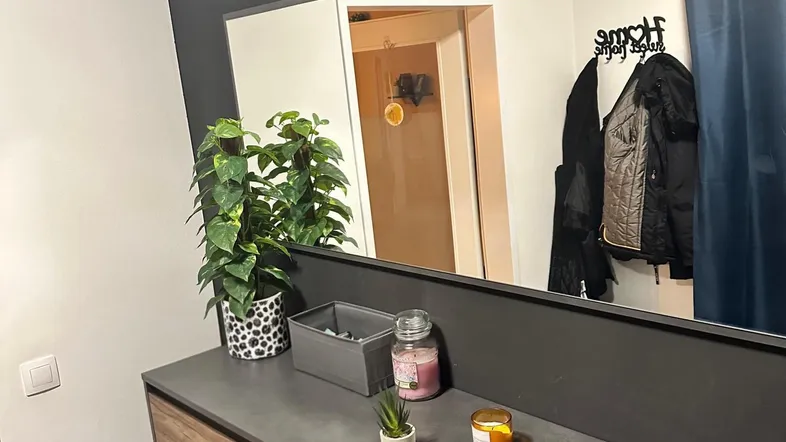 Moderner Eingangsbereich mit Holzschuhschrank, großem Spiegel und dekorativen Elementen an der Wand.
