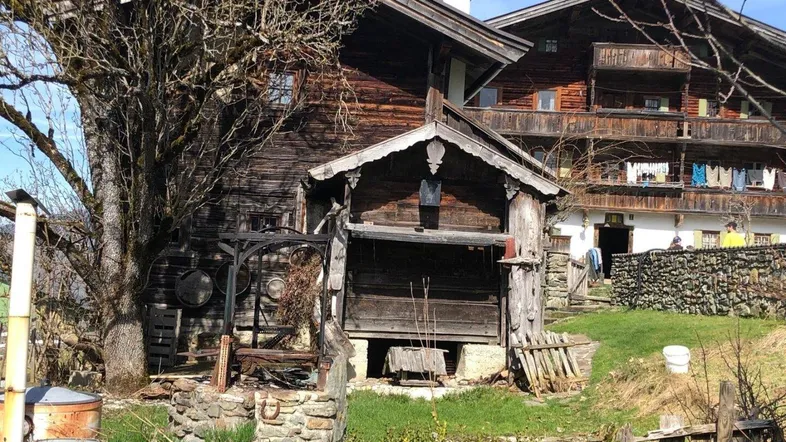 Traditionelles Holzhaus mit rustikalen Elementen, altem Baumbestand und ländlicher Umgebung.
