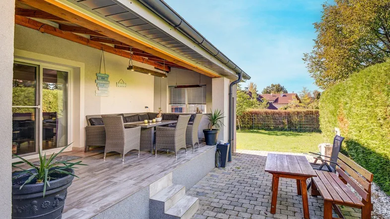 Überdachte Terrasse mit bequemen Gartenmöbeln und Blick auf den gepflegten Garten.
