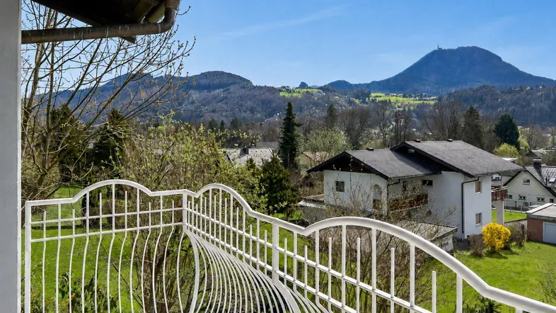 Heller Balkon mit schmiedeeisernem Geländer und weitem Blick auf die umliegende Berglandschaft.