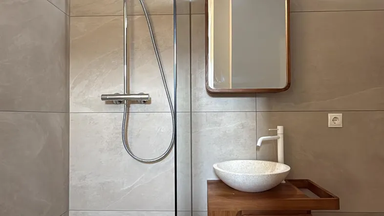 Modernes Badezimmer mit begehbarer Dusche, stilvollem Waschbecken und Holzunterschrank.