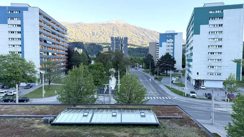 Weitblick auf Wohngebäude, grüne Umgebung und Berge im Hintergrund von einem Dach mit Oberlichtern.