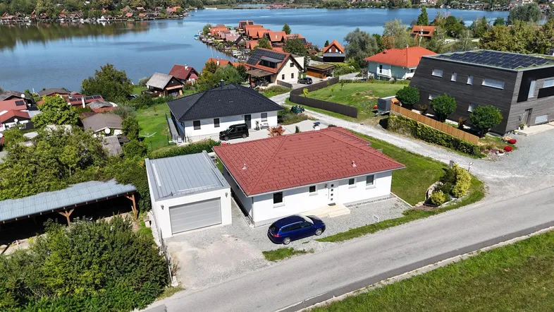 Luftaufnahme eines Hauses mit Garage und Seeblick in einer Wohnsiedlung.