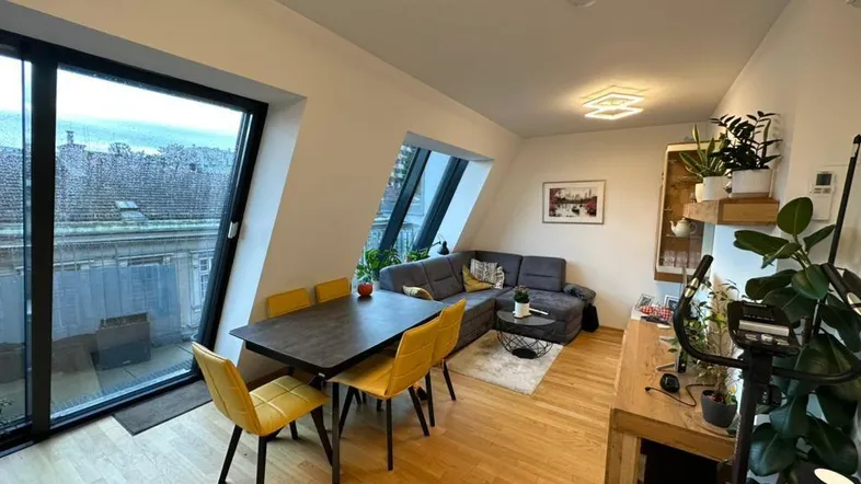 Offener Wohn- und Essbereich mit Holzboden, bequemer Couch und großzügigem Zugang zur Terrasse.