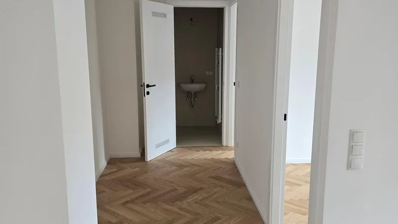 Heller Flur mit Fischgrätparkettboden und Zugang zu einem modernen Gäste-WC.