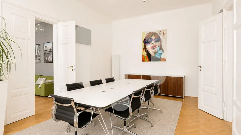 Geräumiger Konferenzraum mit modernem Tisch, bequemen Stühlen und Holzboden, ideal für Besprechungen.
