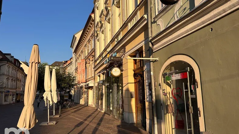 Eine belebte Straße mit historischen Gebäuden und Geschäften im warmen Abendlicht.