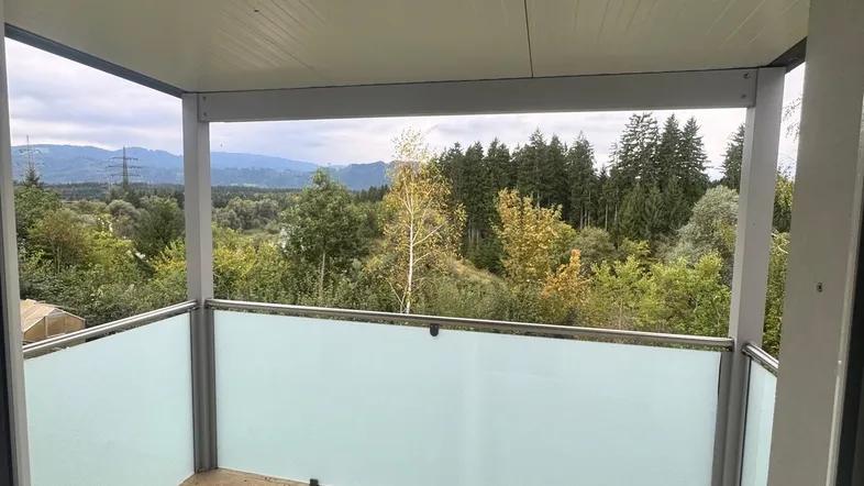 Geräumiger Balkon mit Fliesenboden und weitem Blick ins Grüne und auf die umliegenden Berge.