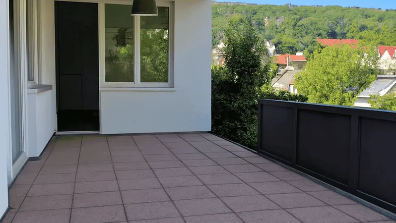 Geräumiger Balkon mit Fliesenboden und weitem Blick ins Grüne und auf die umliegenden Häuser.