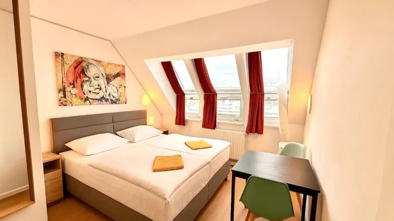 Helles Schlafzimmer mit Doppelbett, Dachschrägen und schrägen Fenstern, modern eingerichtet.