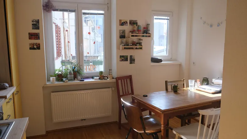 Heller Essbereich mit Holztisch und Heizkörper unter dem Fenster, angrenzend an die Küche.