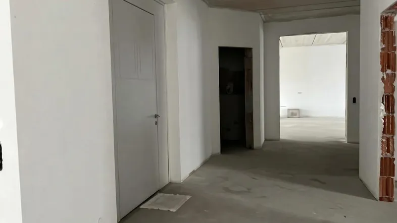 Unfertiger Innenraum mit Betonboden und weißen Wänden, bereit für den weiteren Ausbau.