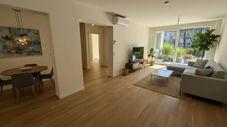 Helles, offenes Wohn- und Esszimmer mit Holzboden und Zugang zur Terrasse, modern eingerichtet.