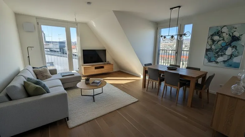 Helles Wohn- und Esszimmer mit Holzboden, modernen Möbeln und Zugang zu einem Balkon.