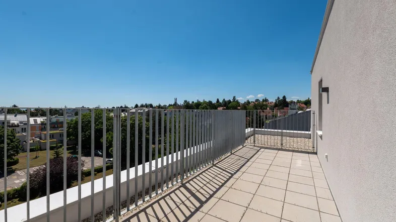 Geräumige Dachterrasse mit Fliesenboden und weitem Blick über die Stadt und grüne Umgebung.