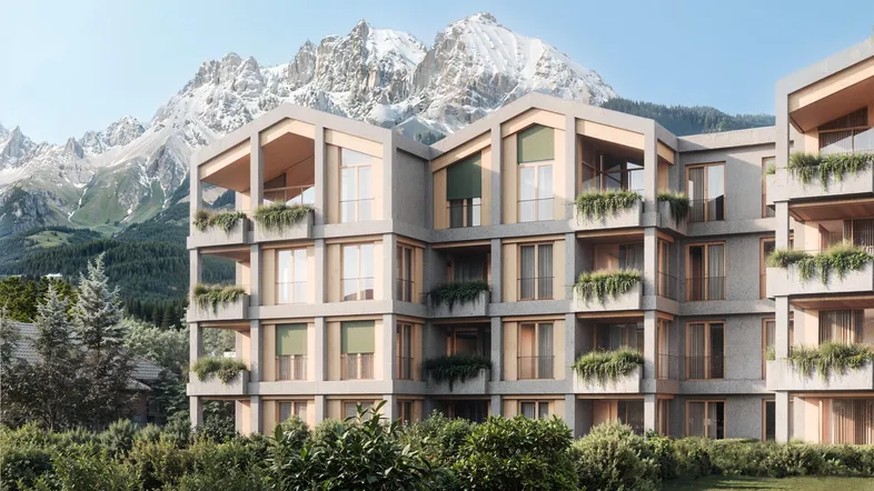 Moderne Wohnanlage mit markanter Architektur, umgeben von Grünflächen und mit beeindruckendem Bergblick.