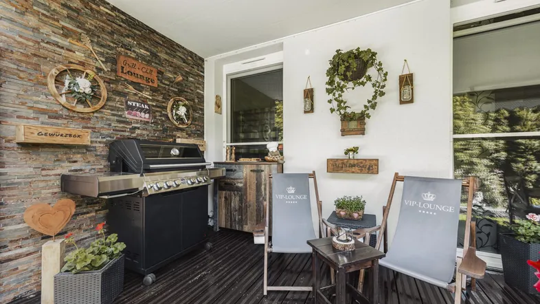 Überdachte Terrasse mit Grillbereich und gemütlichen Sitzgelegenheiten, ideal für gesellige Abende.
