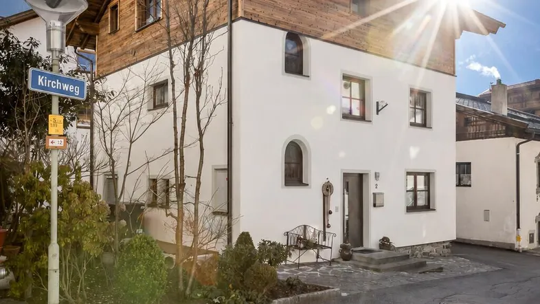 Traditionelles Haus mit Holzelementen und weißer Fassade in sonniger Berglage.