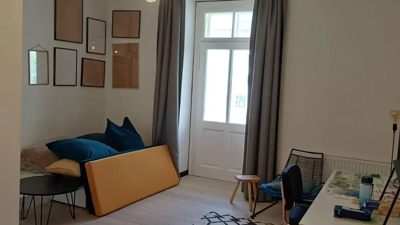 Helles Wohnzimmer mit Holzboden, einem Schreibtisch und einem Tagesbett.