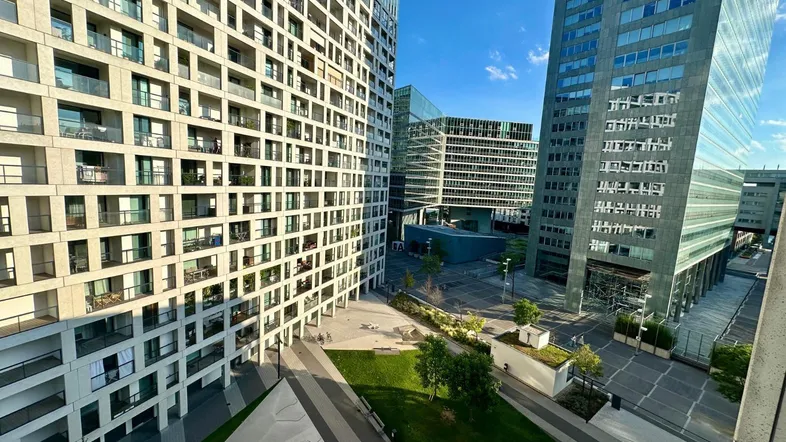 Moderne Wohngebäude mit Balkonen und einer begrünten Außenanlage unter blauem Himmel.