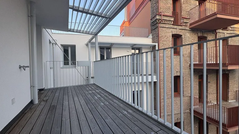 Geräumiger Balkon mit Holzboden und Blick auf die umliegenden Gebäude.