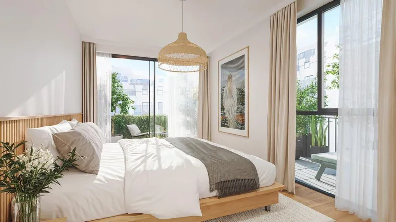 Helles Schlafzimmer mit Holzbett, Parkettboden und Zugang zu einem kleinen Balkon.