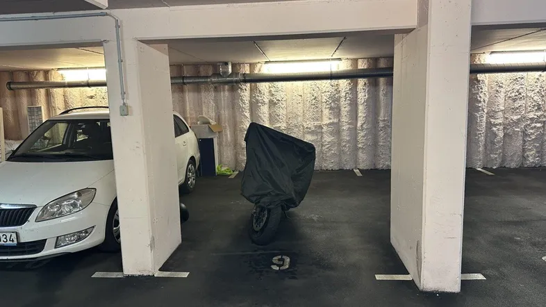 Tiefgarage mit mehreren Stellplätzen, beleuchtet durch Neonröhren, bietet sicheren Parkraum.